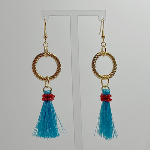 Gold-toned hanging earrings with a gold-plated hoop with hanging blue tassels with red beads. 