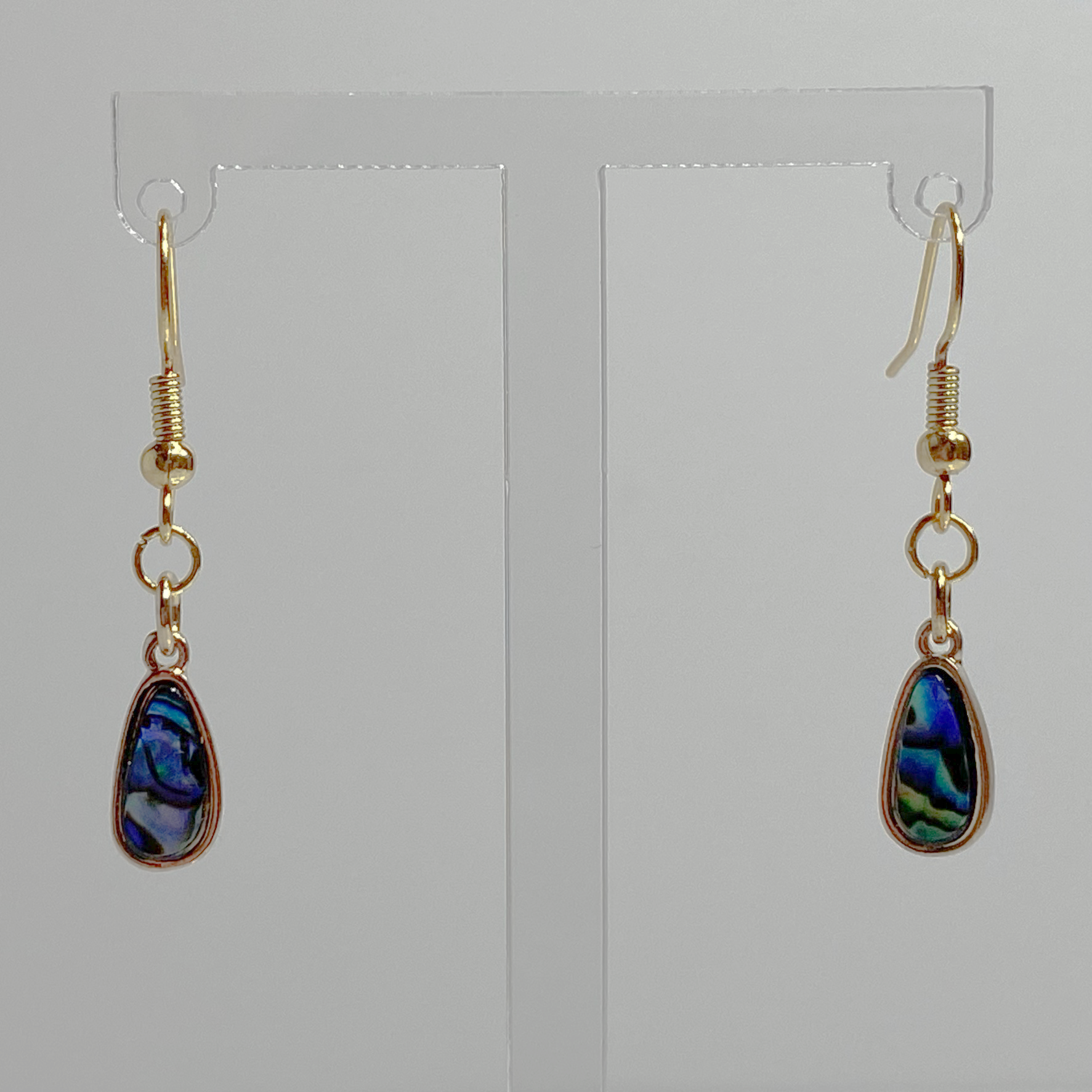 Gold earrings with dangling blue, purple, and green hued marble teardrop charms.