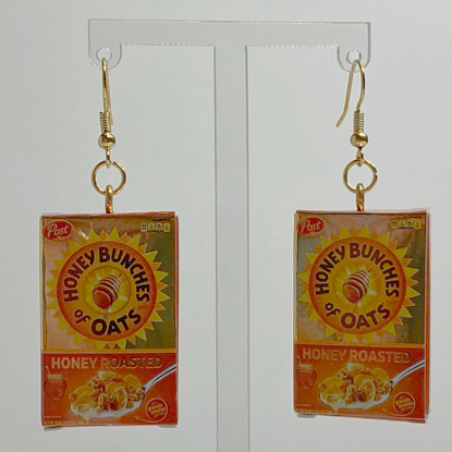 Mini gold Honey Bunches of Oats cereal box earrings on a white backdrop.