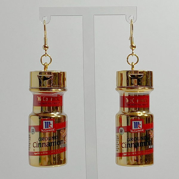 Mini gold McCormick cinnamon spice earrings on a white backdrop.