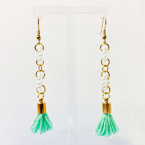Gold-toned hanging earrings with two acrylic pearl rings and sea foam green tassels. 