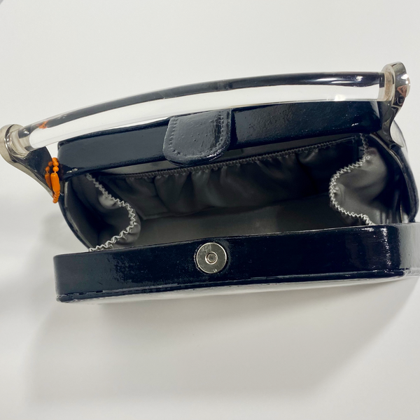 Overheard view of the inside of the purse showing an inside pouch, clear handle, and magnetic clasp. 