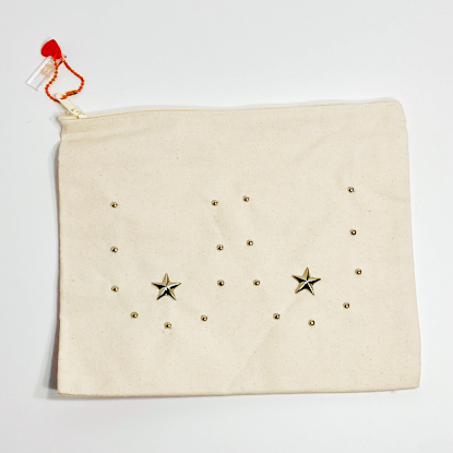 Canvas pouch bedazzaled with silver metal studs to outline the shape of breasts with metal stars for the nipples. The pouch is on a white background.